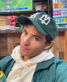 a man in a baseball cap is holding a can of soda and looking at the camera