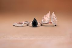 three rings with diamonds and black onyx stone in the shape of two wings, one is shaped like a bird