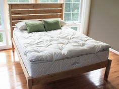 a bed with two pillows on top of it in a room next to a window