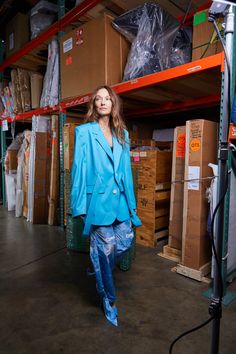 a woman in a blue suit is walking through a warehouse