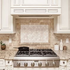 a stove top oven sitting inside of a kitchen next to white cabinets and counter tops