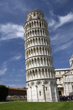 a tall white tower sitting on top of a lush green field under a blue sky