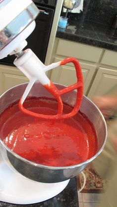 a hand mixer mixing red liquid in a bowl