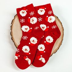 Red ankle socks with a santa claus head and snowflake design. These socks are pictured on a piece of wood on a white background. Cute Christmas Gift Socks, Playful Winter Socks For Gift, Playful Winter Gift Socks, Playful Christmas Socks For Stocking Stuffers, Novelty Socks For Winter Gift, Novelty Winter Socks For Gifts, Novelty Winter Socks For Gift, Novelty Winter Socks As Gift, Cute Red Socks For Gifts