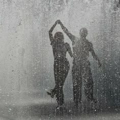 two people standing in the rain with their hands up