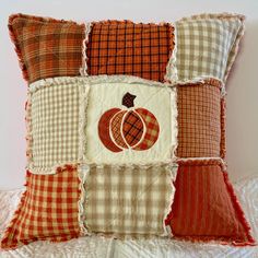 an orange and white patchwork pillow with pumpkins on the front, checkered back