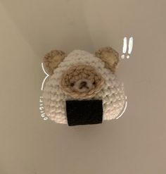 a crocheted sheep head hanging on the wall in front of a white background