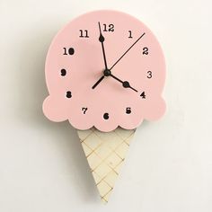 a pink clock with an ice cream cone on it's face is hanging from the wall