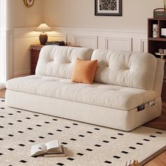 a white couch sitting on top of a wooden floor next to a book shelf filled with books