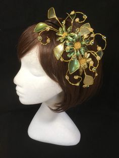 Green floral fascinator vine perfect for the guest or bride who is looking for a beautiful bespoke design. This design is a beautiful selection of glass effect leaves and flowers teamed with crystal swirls and set onto a gold ribbon base tiara band. As with all our designs, this piece can be made exact to the image or in any colour combination to match in with your outfit. If a specific colour is required customers can message over an image of their outfit and accessories, or if time allows cust Green Headband Fascinator For Wedding, Green Fascinator With Handmade Flowers For Party, Green Headband Mini Hat For Wedding, Green Handmade Flowers Wedding Fascinator, Elegant Green Hair Accessories For Wedding, Whimsical Green Headpiece For Parties, Green Wedding Headband Hair Accessory, Green Headband For Wedding, Flower Decorated Headband For Party