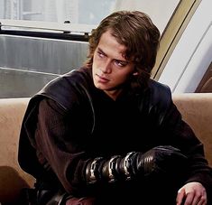 a young man sitting on top of a couch next to a window in a building