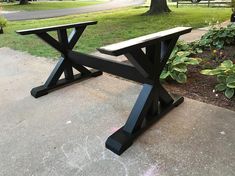 a wooden bench sitting on top of a cement slab in front of a green tree