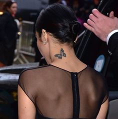 the back of a woman's neck with a butterfly tattoo on her left side