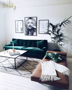 a living room with green couches and pictures on the wall above them, along with a rug