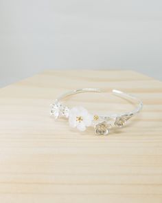 As delicate as it looks, the mixture of a matt finished white crystal flower and four other sterling silver flowers sitting on the brushed finish tree branch make this bangle the perfect accessory for the season.details: matt finished white crystal brushed finish 925 sterling silver bangle size approx, 5.7cm x 6.1cm one size self-adjustable helpful tips: due to the natural softness of sterling silver, when adjusting the bangle size, try to use both hands to gently pull both sides of the bangle band millimetre by millimetre, avoid pulling drastically in order to keep the bangle in shape. After putting the bangle on your wrist, gently squeeze back together both sides of the band to tighten it. In order to keep the sterling silver jewelry always shining, try to keep jewelry away from water, p The Bangles Band, Bangles Jewelry Designs, Sterling Silver Bangle, Open Bangle, Sterling Silver Flowers, Sterling Silver Bangles, Silver Bangle, Crystal Flower, White Crystal