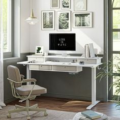 a white desk with a computer on it in front of some pictures and a chair