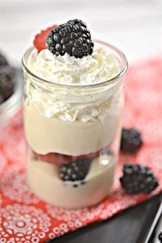 a dessert in a jar with whipped cream and blackberries on the top is ready to be eaten