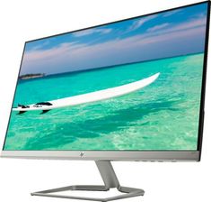 a computer monitor sitting on top of a white table next to a surfboard in the ocean