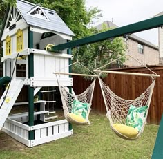 two hammock chairs and a swing set in a backyard with a tree house