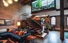 a living room filled with furniture next to a spiral stair case in front of a brick wall