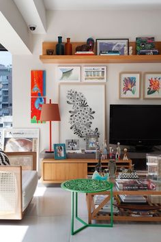 a living room filled with furniture and a flat screen tv on top of a wooden shelf