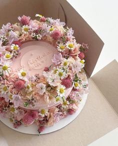 there is a cake with flowers on it in the shape of a flower wreath that says happy birthday