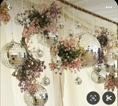 several disco balls hanging from the ceiling with pink flowers in them and other decorations below