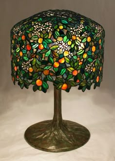 a lamp that is sitting on top of a white tablecloth with oranges and leaves