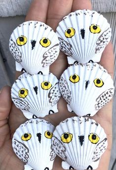 four scallop shells with yellow eyes are held in someone's hand,