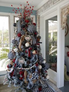 a christmas tree decorated with black and white plaid ribbon, red berries, buffalo head ornaments and an animal ornament