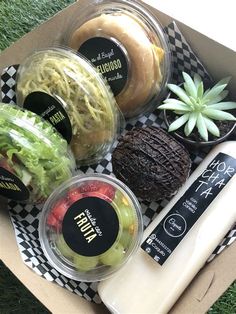 an open box filled with assorted food items on top of a checkered table cloth