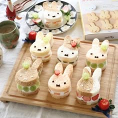 several sandwiches are arranged in the shape of buns with bunny faces on them, along with strawberries and grapes