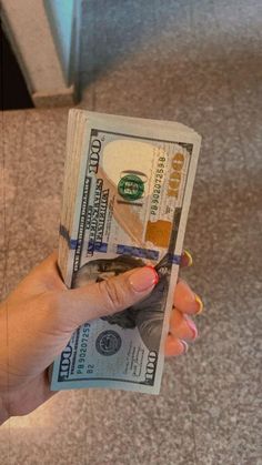 a person holding up a stack of money in their hand on the floor at an airport