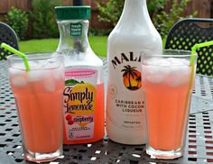 two bottles and three glasses sitting on a table with drinks in front of the bottles