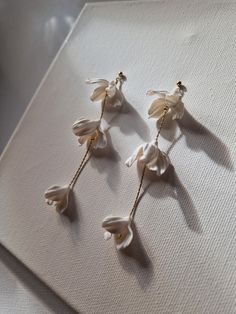 three pairs of white flower earrings on top of a table