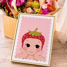 a card with an image of a baby in a strawberry hat on it next to flowers