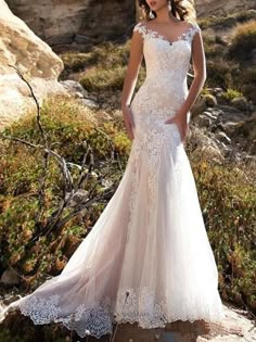 a woman in a wedding dress standing on rocks