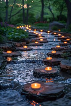 many lit candles are floating in the water near some rocks and stones on the ground