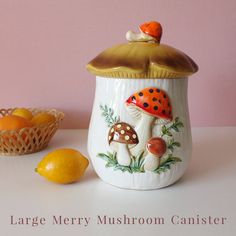 a ceramic jar with mushrooms and oranges next to it