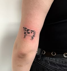 a small cow tattoo on the left arm and shoulder, with black dots around it