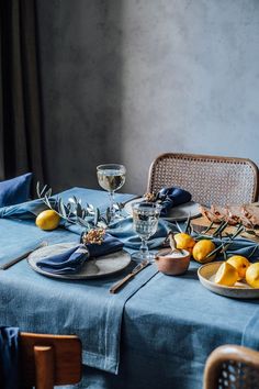 the table is set with blue linens and lemons