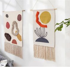 two wall hangings with plants on them