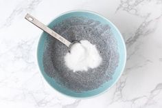 a spoon in a bowl filled with sugar and powder on top of a marble counter