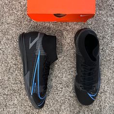 a pair of black and blue shoes sitting next to an orange box on the floor