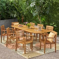 an outdoor dining table and chairs set up on a rug in front of some trees