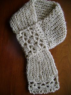 a white knitted scarf laying on top of a wooden table