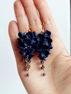 a hand holding some kind of blue flower earrings