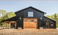 a large black barn with two garages and an open front door on the side