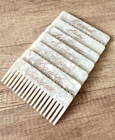 five white combs with gold writing on them sitting on a wooden table next to each other