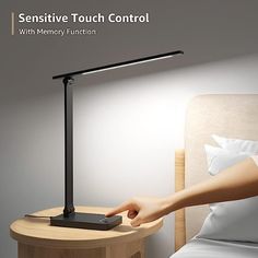 a person is pointing at a lamp on a bedside table